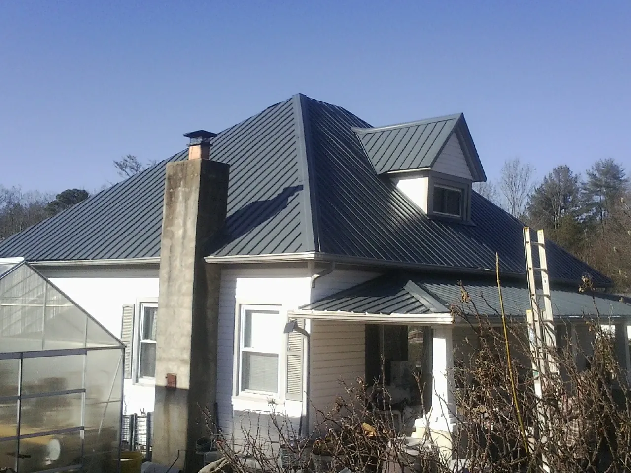 Dark blue standing seam metal roof on a white farmhouse with dormer — Slate & Tile Roof Repair by Roofing Brothers in Santaquin