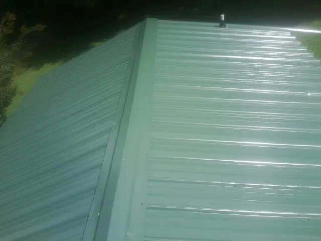 New green metal panels meeting at the ridge of a roof — Flat Roof Repair work by our crew in Santaquin