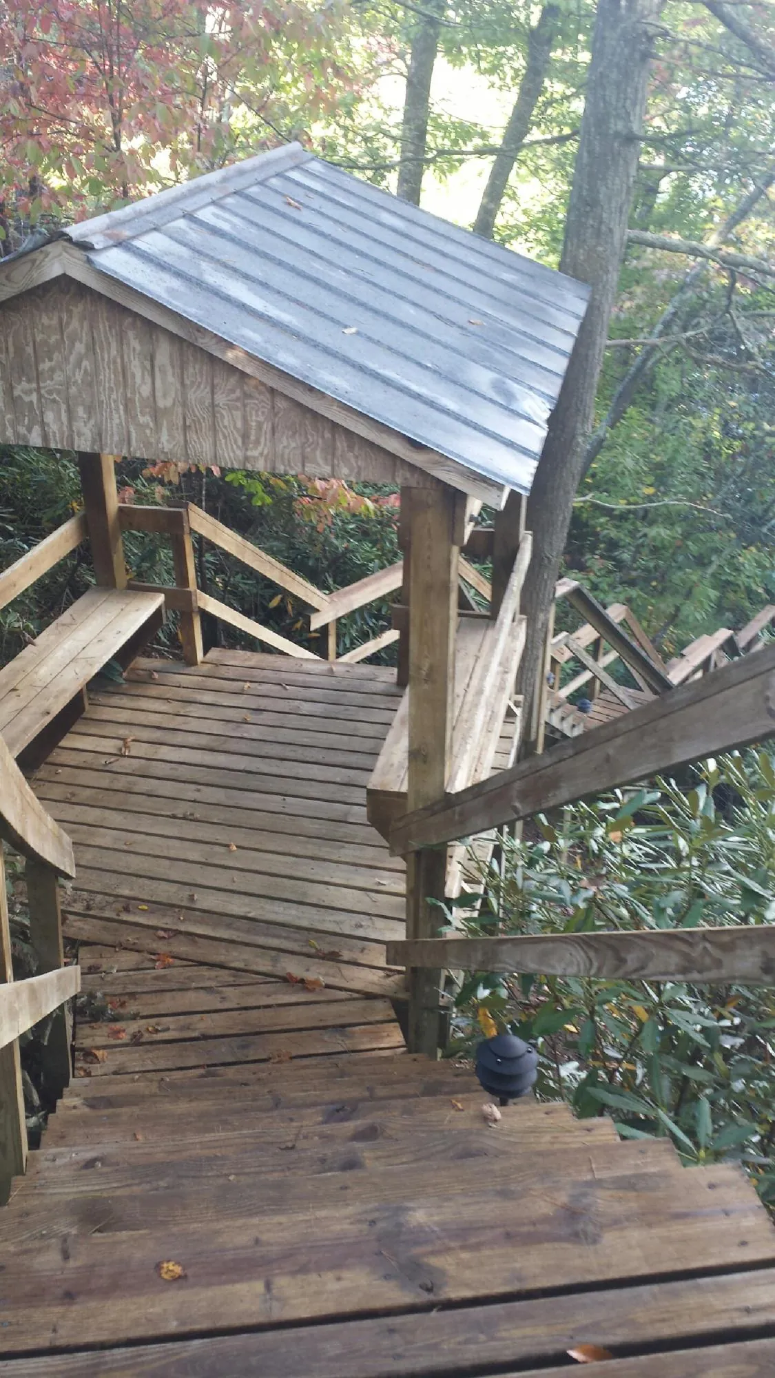 Metal roofed shelter over wooden steps on a wooded walkway — Skylight Repair & Installation work by our crew in Santaquin