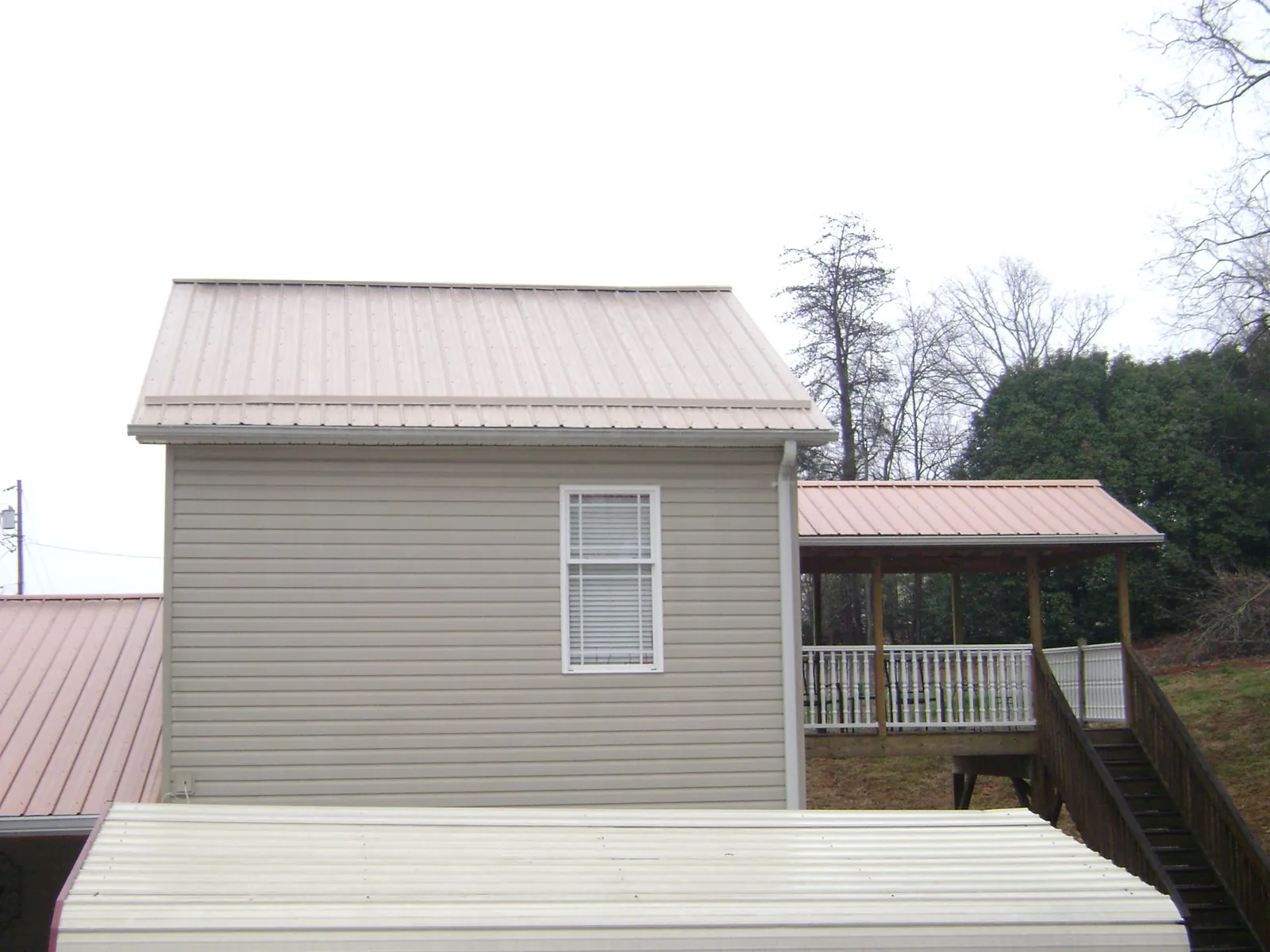 Tan metal roofs on a two story addition and attached porch, from a Roof Replacement job in Santaquin