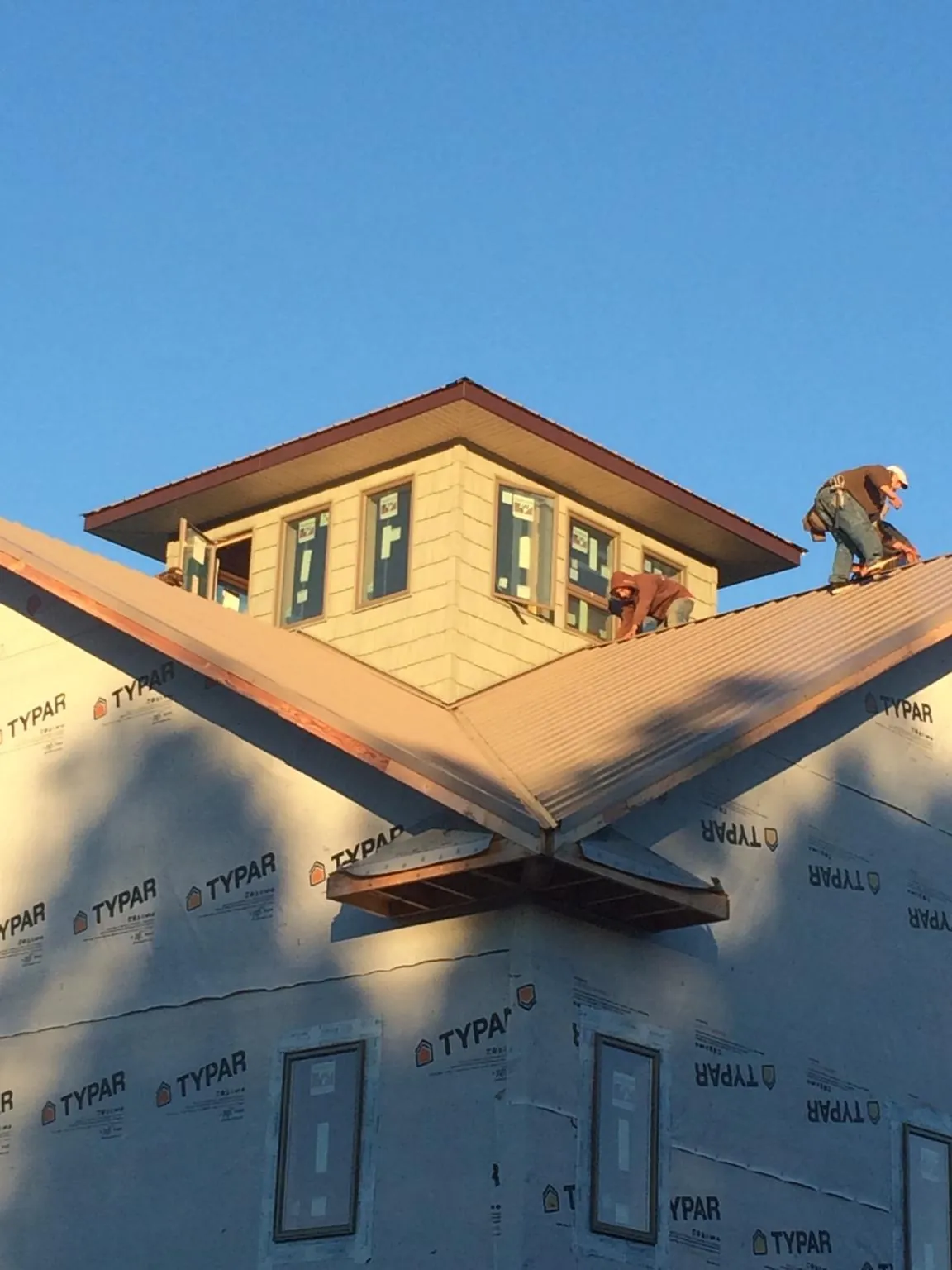 Roofers working around a rooftop cupola on a new metal roof at sunset — Roof Waterproofing in Santaquin by Roofing Brothers